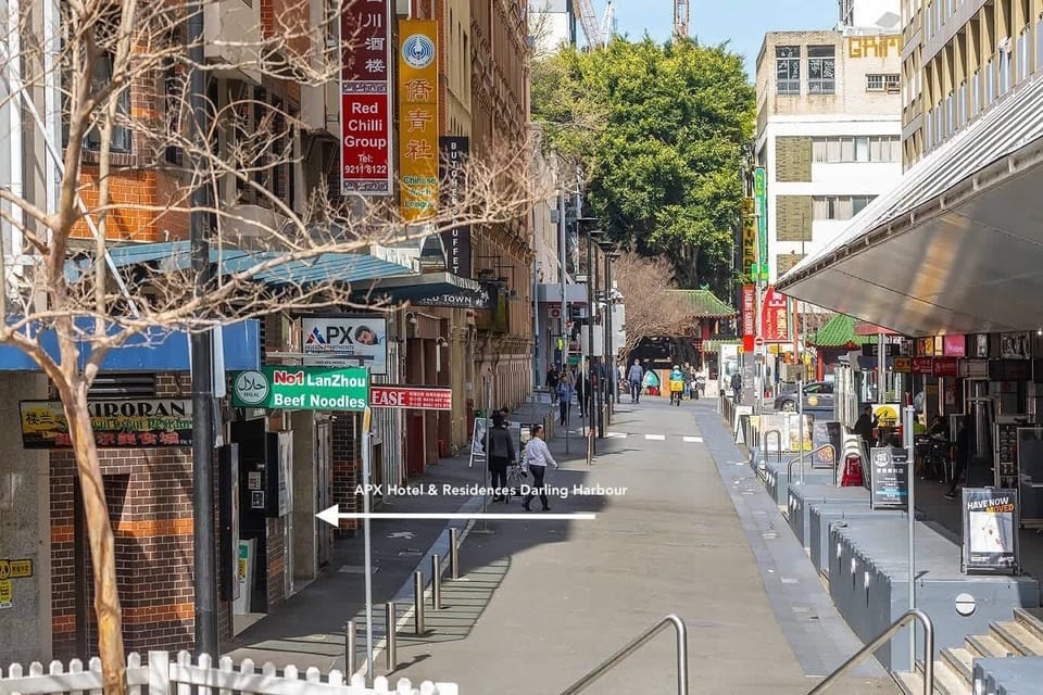 Vibrant city street view with nearby restaurants, shops, and pedestrian activity.