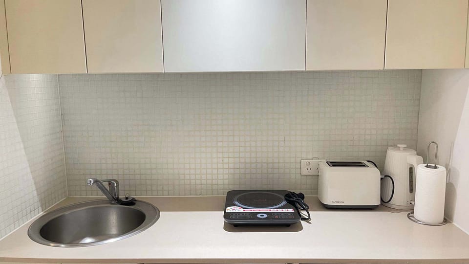 Kitchen counter area with sink, cooktop, kettle, and essential appliances.