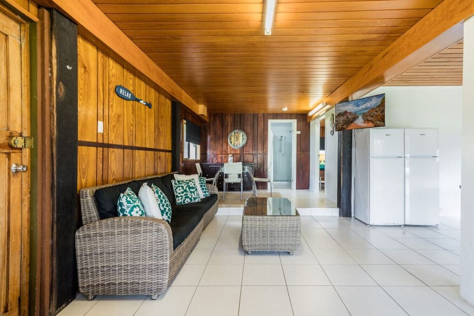 Living + dining with timber walls, wicker sofa, and coastal décor. Family‑friendly space with rustic charm and modern comfort.
