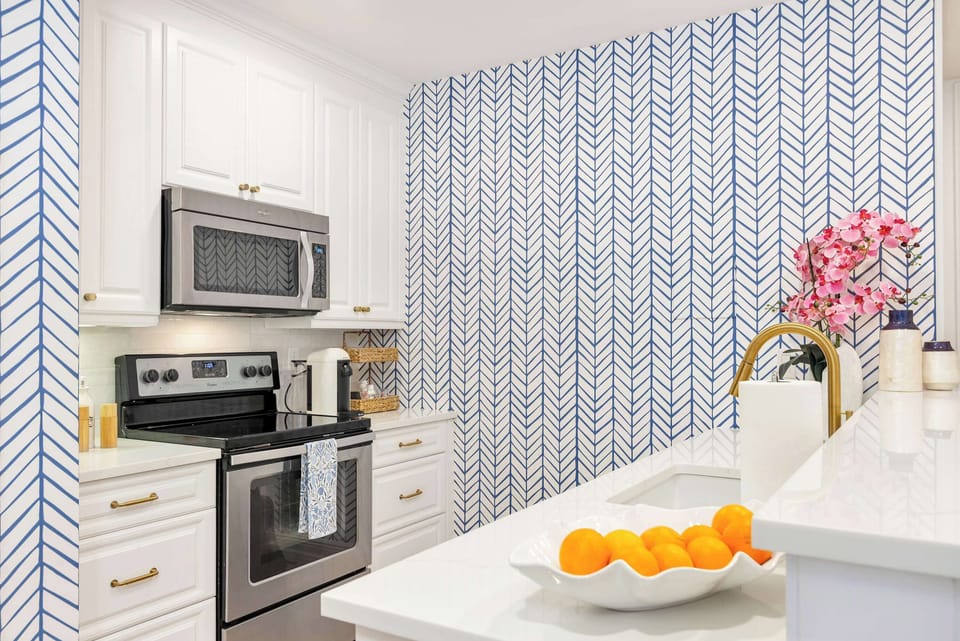 Modern kitchen with stainless steel appliances and patterned blue accent wall.