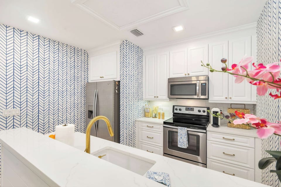 Modern kitchen with stainless steel appliances and patterned blue wallpaper