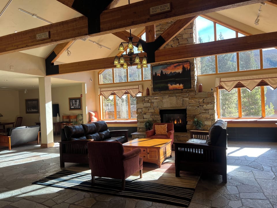 Unwind in this stunning mountain retreat where exposed timber beams frame panoramic forest views. Sink into plush leather seating by the crackling stone fireplace as natural light floods through soaring windows.