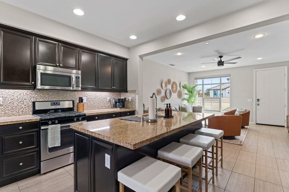 Modern kitchen w/ granite island, bar seating & stainless appliances for easy meals