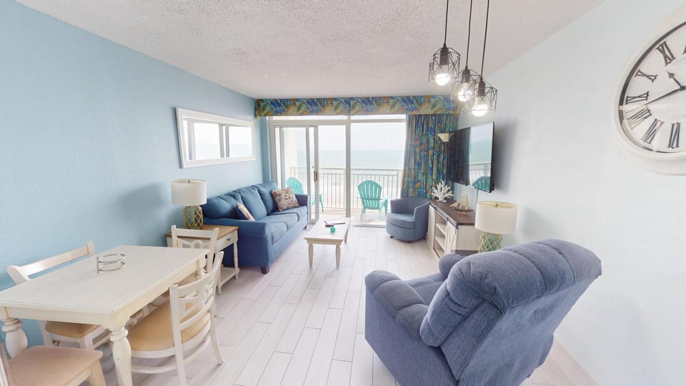 Living room with ocean views - Comfortable living space featuring cozy seating, a flat-screen TV, and large windows that fill the room with natural light and ocean scenery.