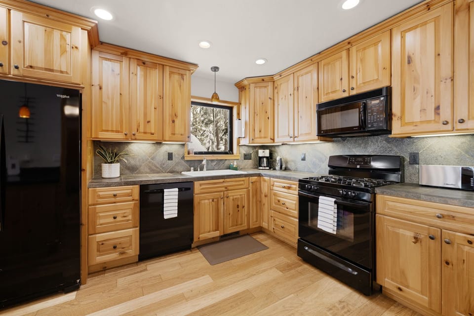 The kitchen boasts dark quartz countertops, sleek appliances, and a gas range