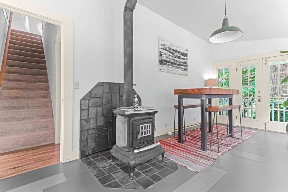 Relax in the back living room, where large windows offer beautiful views of the backyard. This inviting space features a cozy wood stove for chilly evenings, a comfortable sofa, and a high-top table perfect for a casual snack or a game of cards.