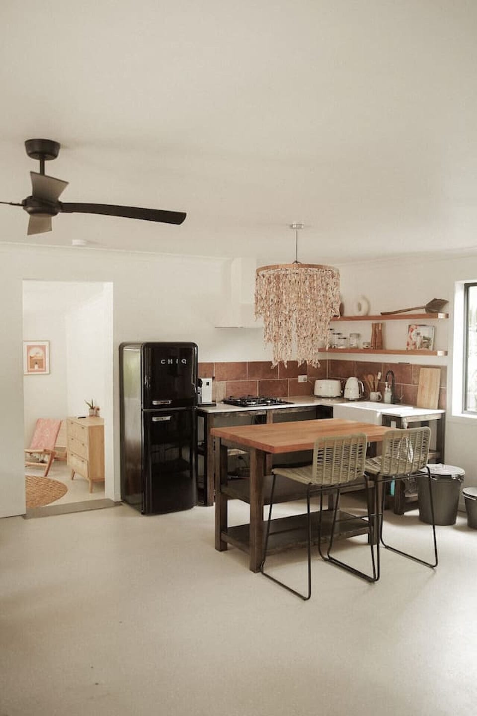 This spacious kitchen features a beautiful island with seating for two, perfect for casual meals or entertaining. A unique shell lamp adds coastal charm, whilst the large fridge ensures plenty of space for all your culinary needs.