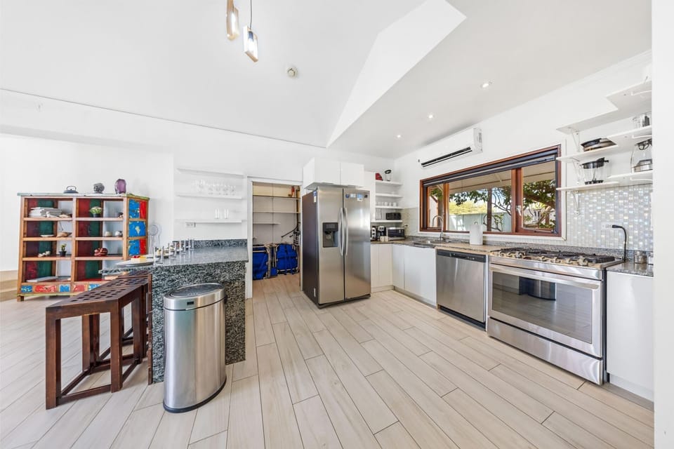 A sleek, sunlit kitchen with stainless steel appliances, a granite island, and warm wooden accents.