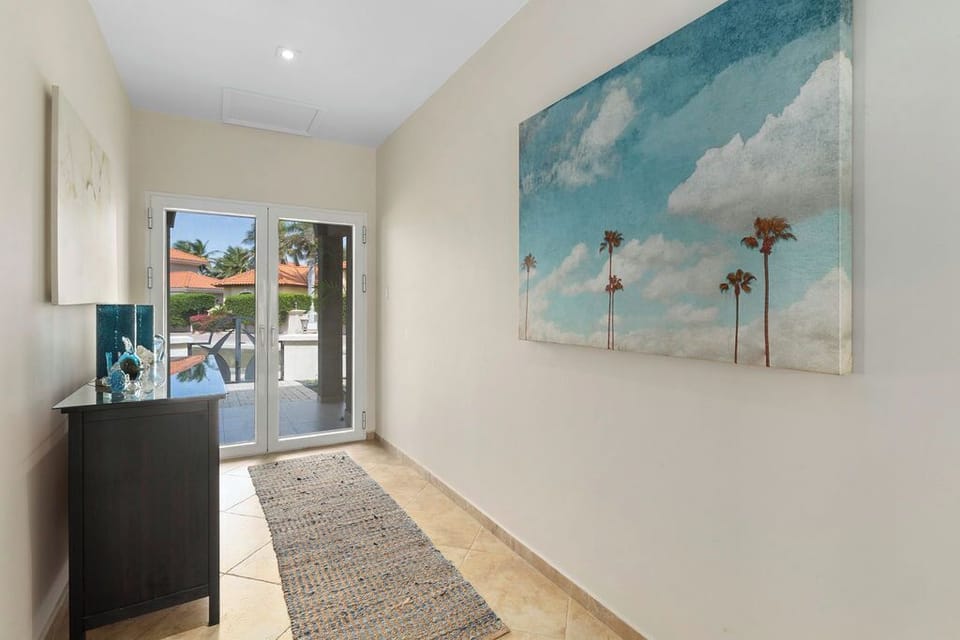 The modern and elegantly furnished living area features plush leather seating, a wall-mounted flat-screen TV, and an open layout—perfect for relaxing after a day of island adventures.