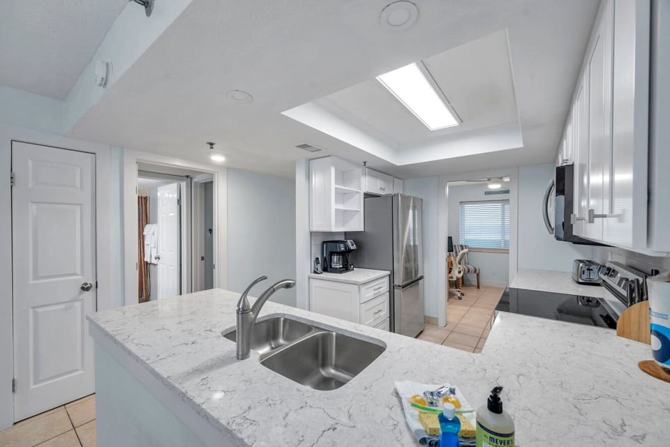 Bright, open kitchen w/ white cabinetry & a clear view into the living space.