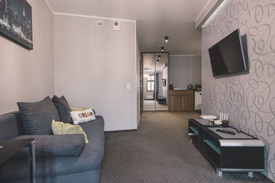 A spacious interior with a designer sofa and TV. A perfect place for business and leisure stays in the city center.
