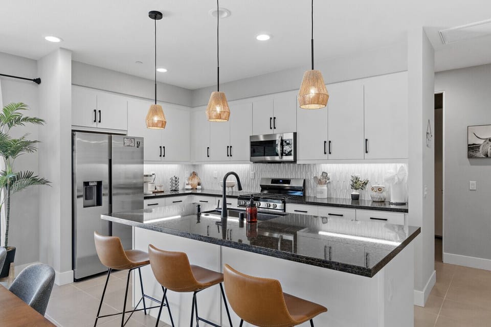 Sleek kitchen w/ island seating, stainless appliances & stylish pendant lighting