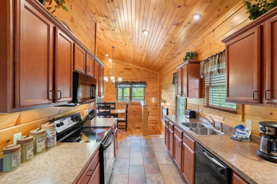 Enter the cabin through the fully-equipped kitchen. It includes cookware, dishware, silverware, bakeware, and everything you need to enjoy meals inside.