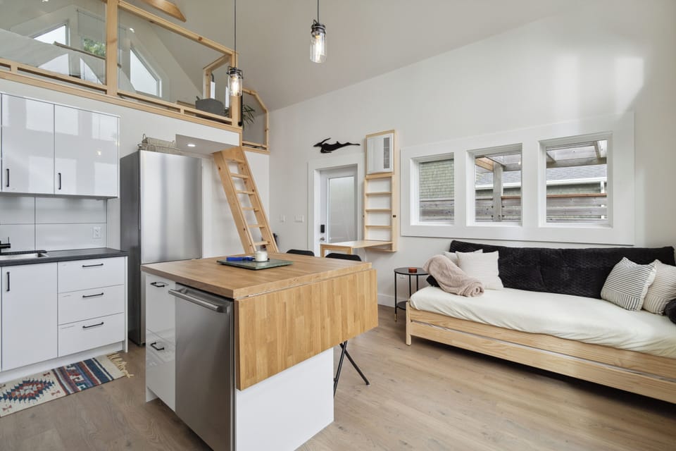 Stylish tiny loft with a cozy daybed, modern kitchen, and lofted sleeping area.