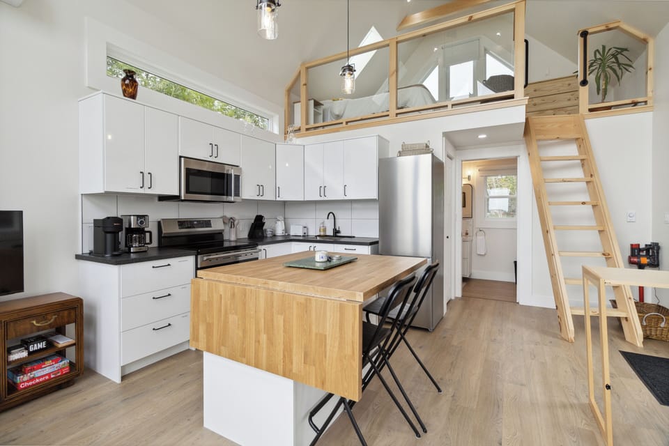Bright tiny loft with a modern kitchen, lofted bedroom, and cozy dining space.