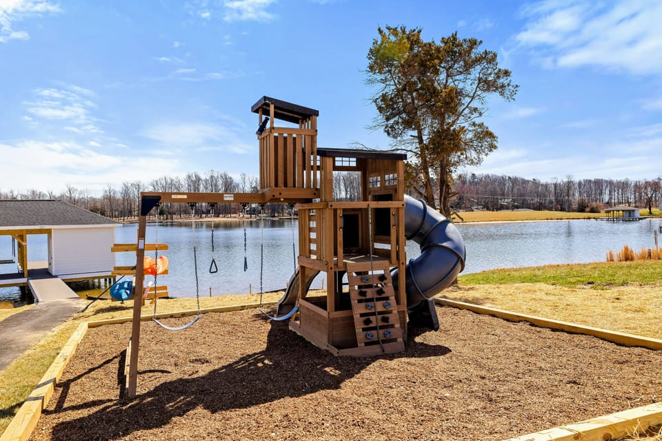 Children's Play Area: Delightful lakeside playset offering hours of fun, safely designed with slides, swings, and climbing features, all with picturesque lake views.
