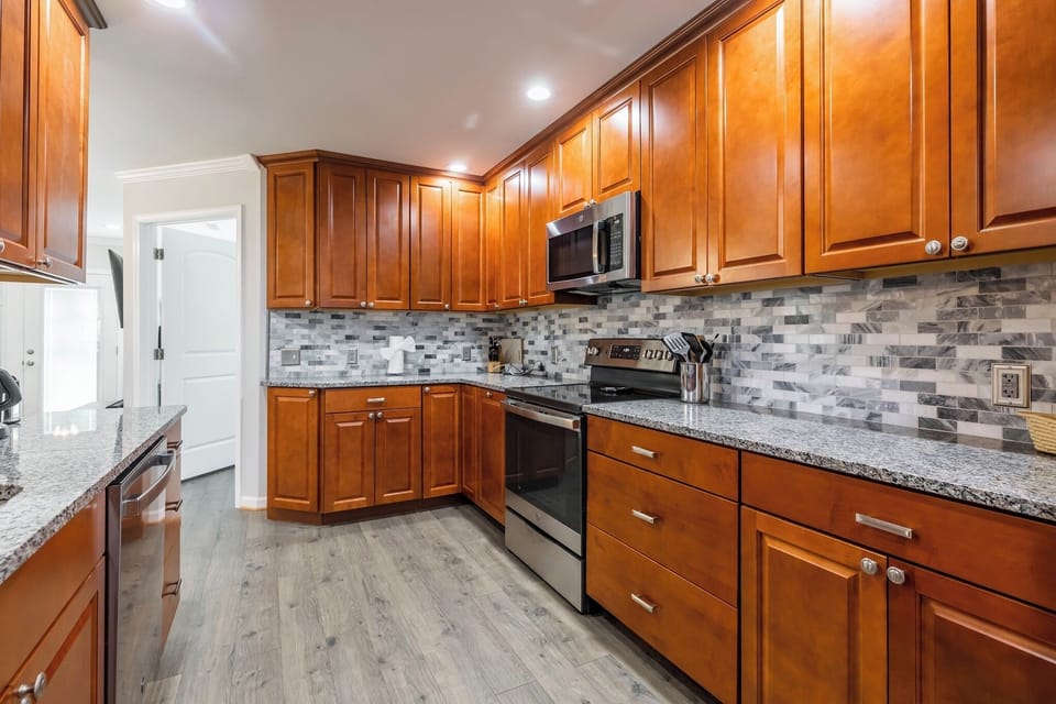 Fully equipped with granite countertops, warm wood cabinets, and stainless steel appliances.
