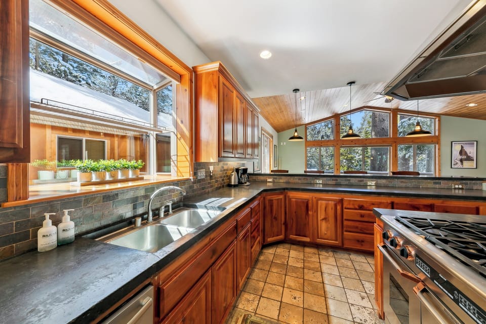 Cook in your spacious gourmet kitchen featuring rich wood cabinets, granite countertops, and abundant natural light streaming through picture windows.