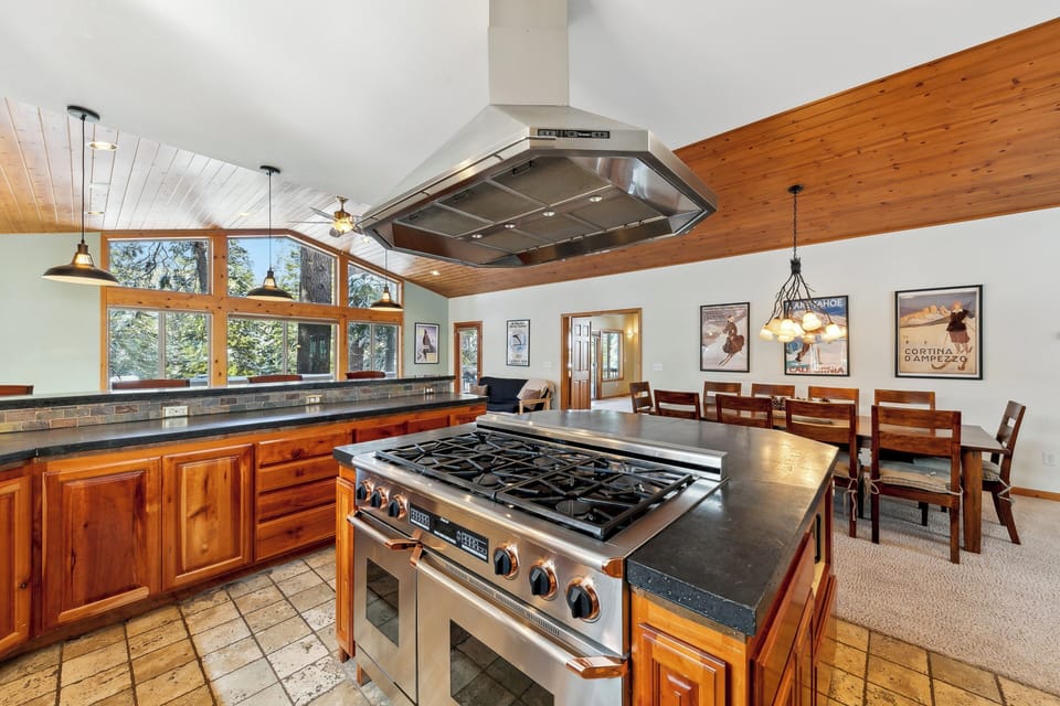 Your gourmet kitchen features professional-grade appliances and rich wood cabinetry, perfect for preparing memorable meals with stunning forest views.