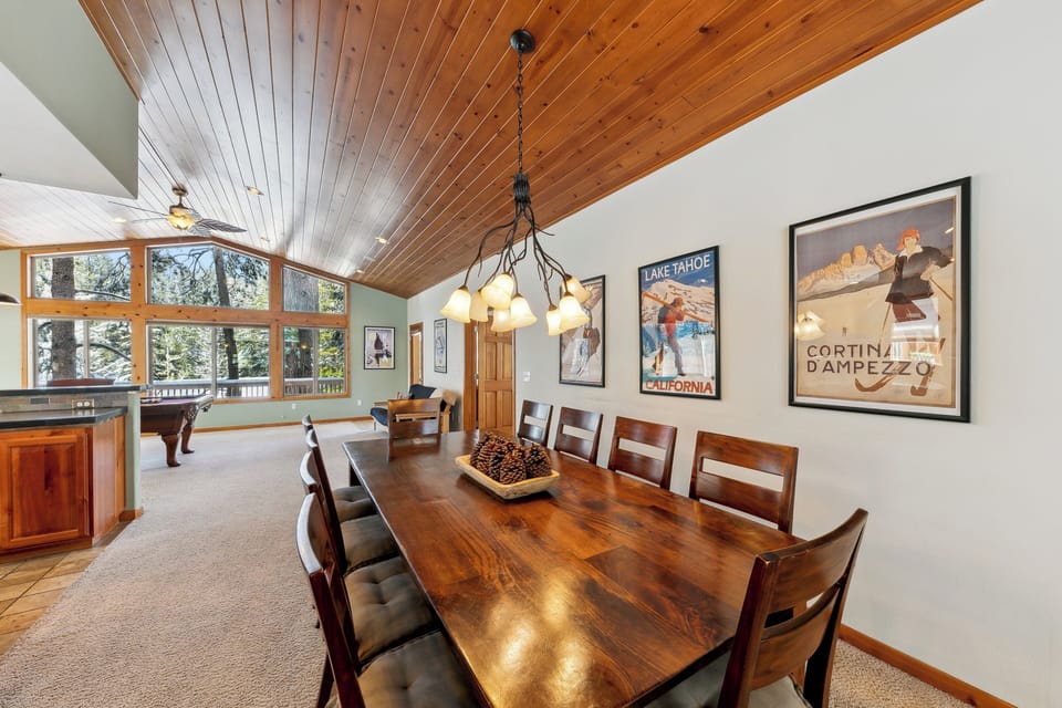 Gather around your beautiful wood dining table under soaring ceilings, with natural light streaming through expansive windows overlooking the forest.