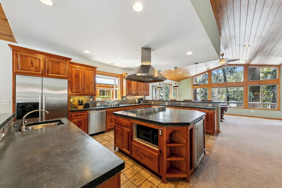 Your dream kitchen awaits with gleaming granite counters, rich wood cabinets, and stunning forest views through floor-to-ceiling windows.