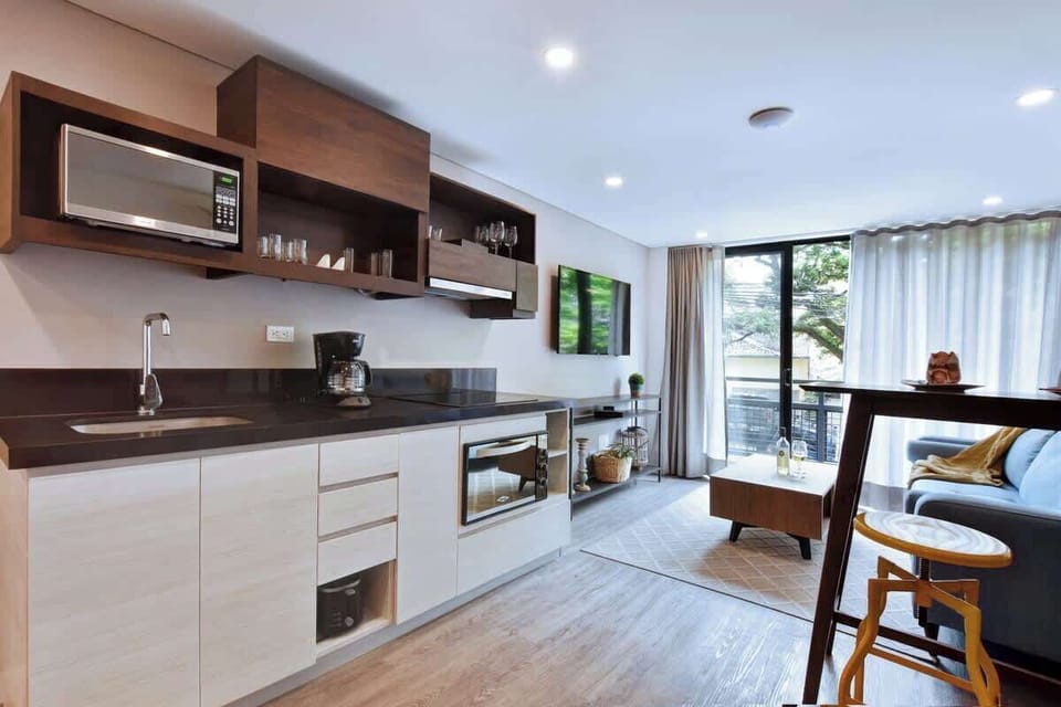 Kitchen connecting to living room and balcony. High table and bar chairs for dining. 