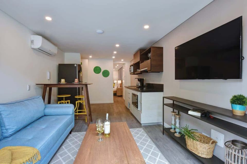 Living room connecting to kitchen. TV, A/C and access to balcony. 