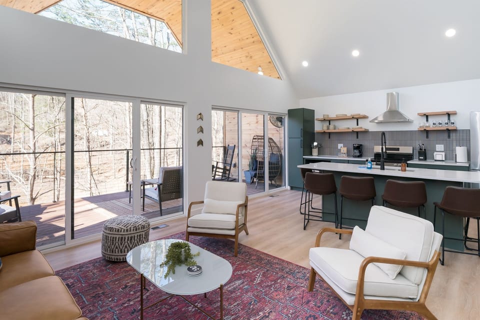 Bask in natural light and pond views from this stylish open-concept living area—featuring a fully equipped kitchen, cozy seating, and direct access to the outdoor deck.ng room
