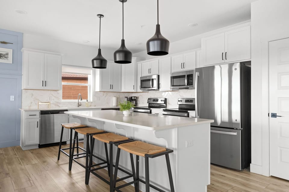 - Whip up meals in this kitchen with black pendant lights & sleek countertops
- Fully equipped with stainless steel appliances including double ovens & a large fridge
- Island seating for four makes it perfect for breakfast chats or evening cocktails