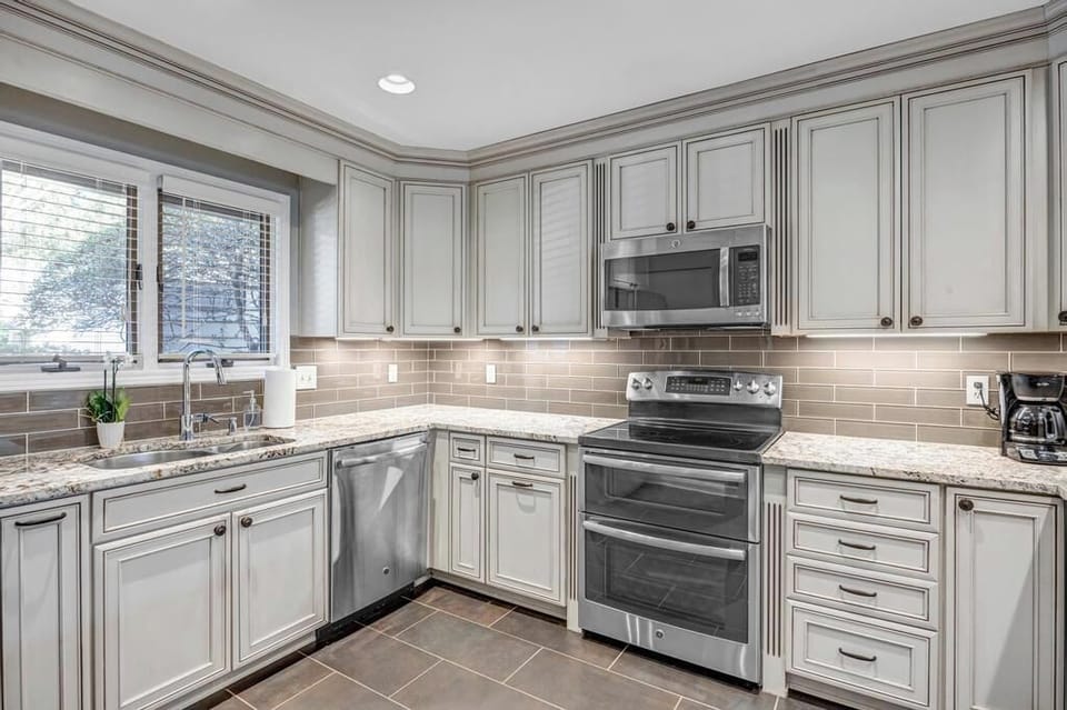 - Gourmet kitchen with granite counters, stainless appliances, and stylish backsplash
- Gray cabinetry and under cabinet lighting create a sleek, upscale atmosphere
- Fully equipped for meal prep, morning coffee, or extended vacation cooking