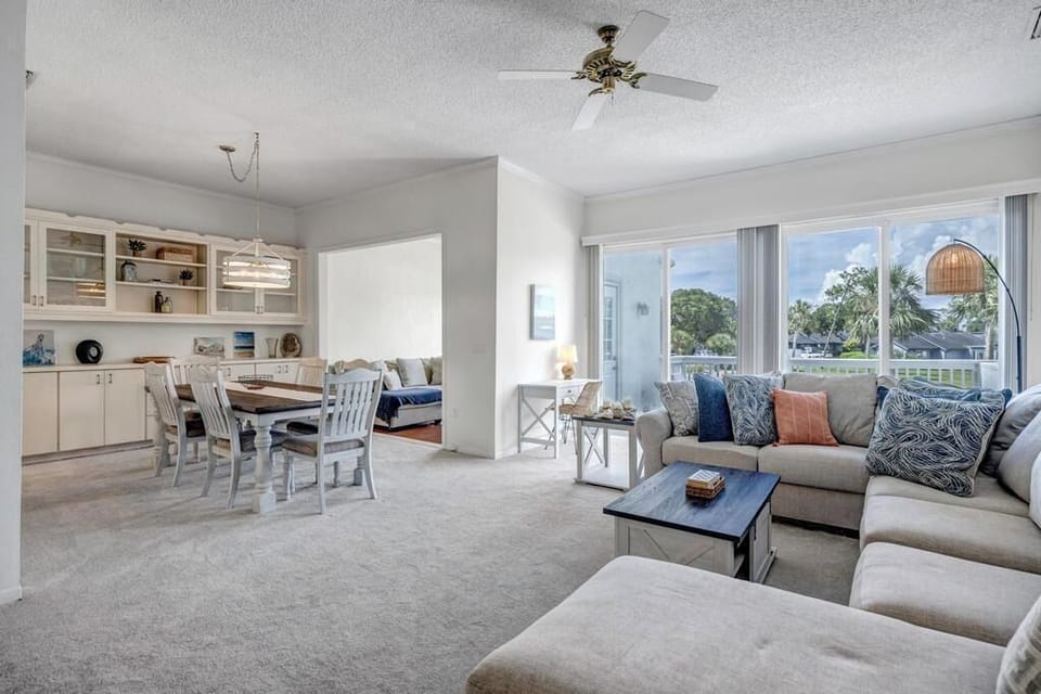 - Spacious living room with large sectional, bright windows, and beachy color accents
- Dining area and sunlit alcove provide space for group meals or laid back lounging
- Open layout creates a perfect setting for connection, comfort, and relaxation