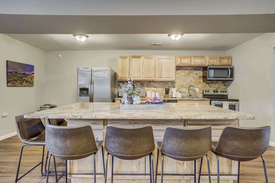 The fully equipped kitchen features stainless steel appliances, a spacious island with bar seating, and a stylish stone backsplash. Perfect for preparing delicious meals while staying connected with family and friends.





