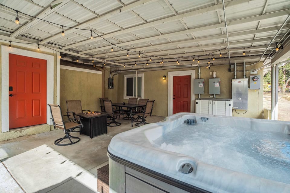 Enjoy the large, bubbling hot tub located on the covered concrete patio. This outdoor space also features a dining table with chairs, a small fire pit table, and string lights overhead. Please note that this area is shared with other units