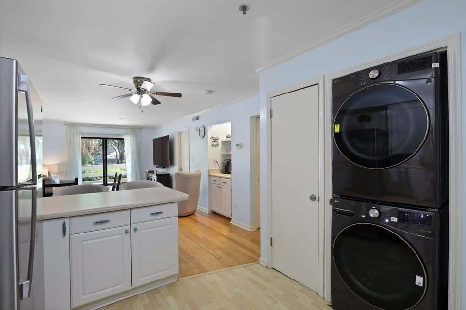 A fully equipped kitchen with sleek white cabinetry and stainless steel appliances.