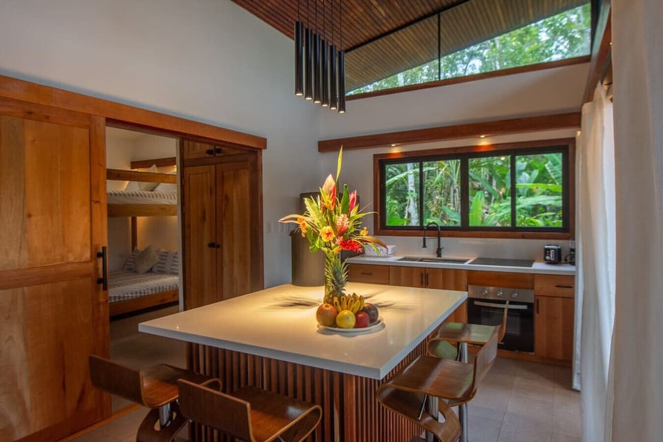 Fully equipped modern kitchen with island seating, natural light, and views of the secondary bedroom in Playa Negra, Casa Kanani