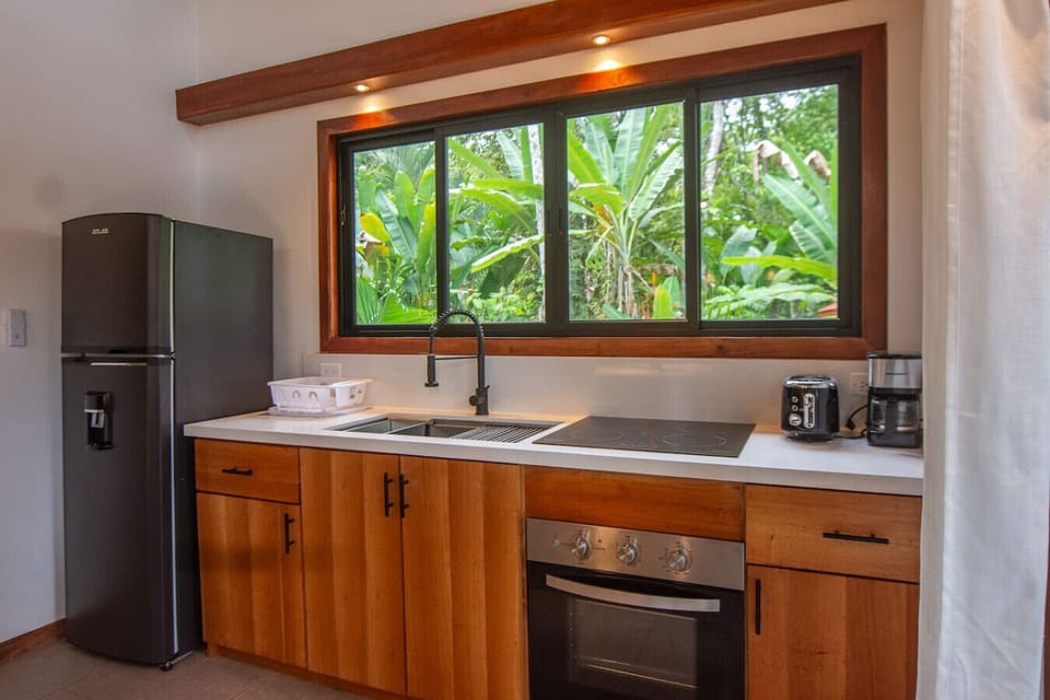 Bright and fully equipped kitchen with modern appliances and lush tropical views in Playa Negra, Casa Kanani