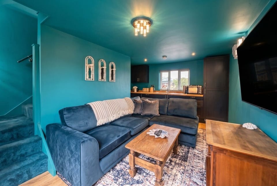 The teal living space opens into a compact kitchenette, giving guests their own cosy retreat.