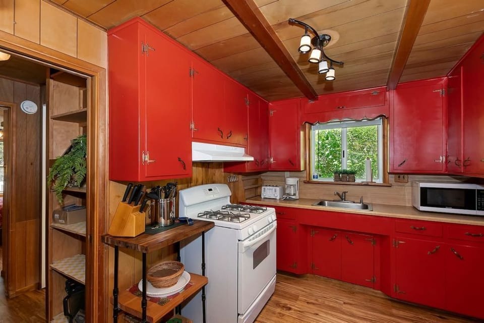 Cook in style with our vibrant kitchen, featuring red cabinets, rustic wooden walls, and modern amenities for a perfect blend of charm and convenience.