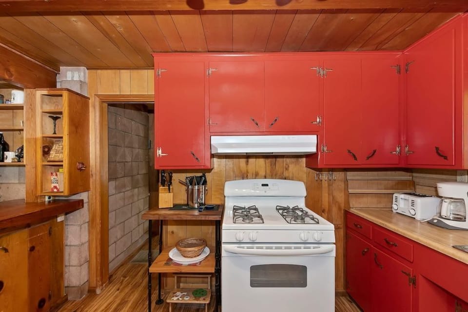 Cook in style with our vibrant kitchen, featuring red cabinets, rustic wooden walls, and modern amenities for a perfect blend of charm and convenience.