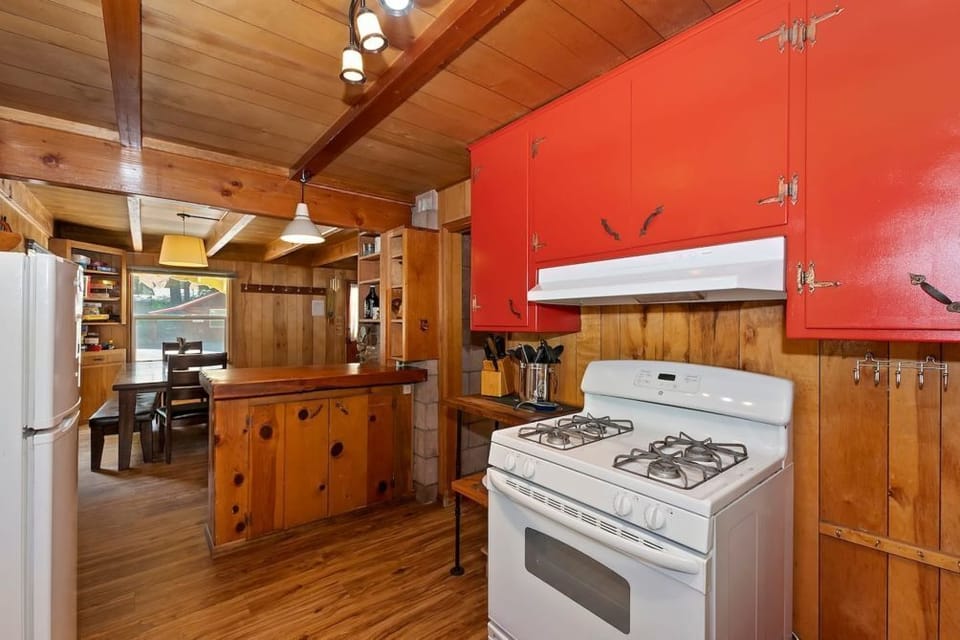 Cook in style with our vibrant kitchen, featuring red cabinets, rustic wooden walls, and modern amenities for a perfect blend of charm and convenience.