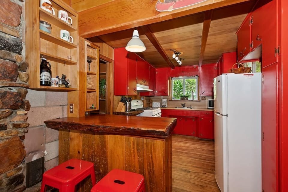 Cook in style with our vibrant kitchen, featuring red cabinets, rustic wooden walls, and modern amenities for a perfect blend of charm and convenience.