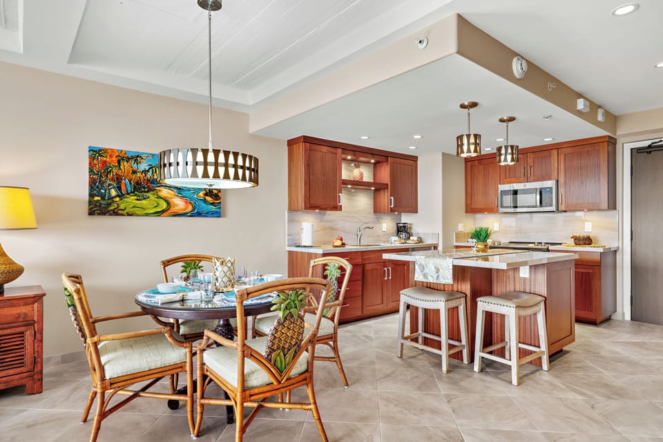This bright, island-inspired dining and kitchen space features warm wood cabinetry, woven textures, and tropical accents, creating a welcoming spot for relaxed meals and casual gatherings in a stylish, coastal setting.