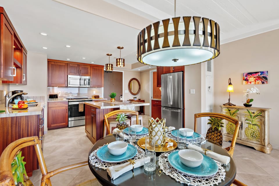 A welcoming dining space set for a relaxed island meal, with tropical touches and a warm, open kitchen perfect for gathering and easy conversation.
