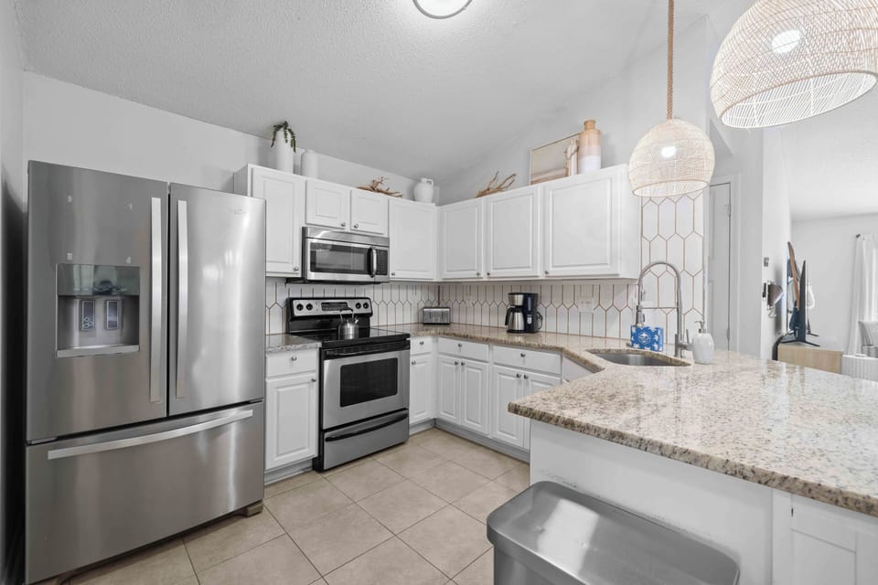 The kitchen features crisp white cabinetry paired with granite countertops.