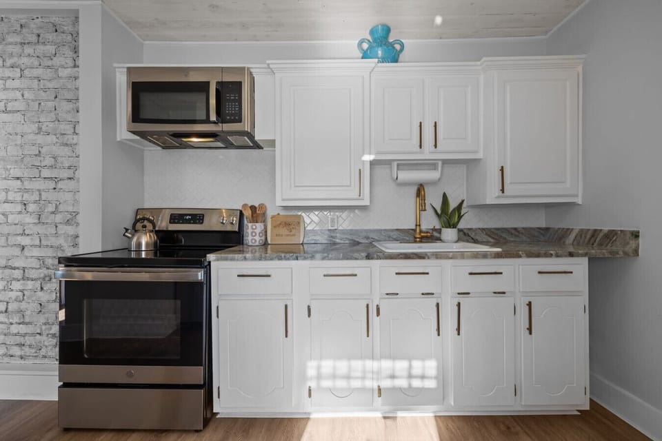 Sun-filled kitchen with stainless steel appliances, white cabinetry, and modern finishes