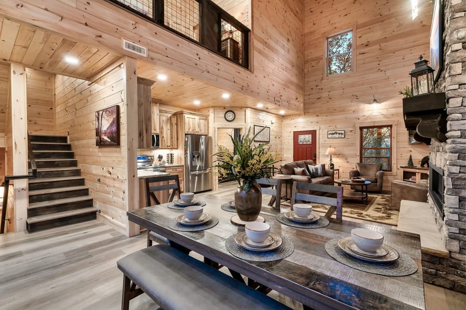 Gather around this rustic dining table, set beneath soaring ceilings and surrounded by warm wood tones for an unforgettable meal with family and friends.