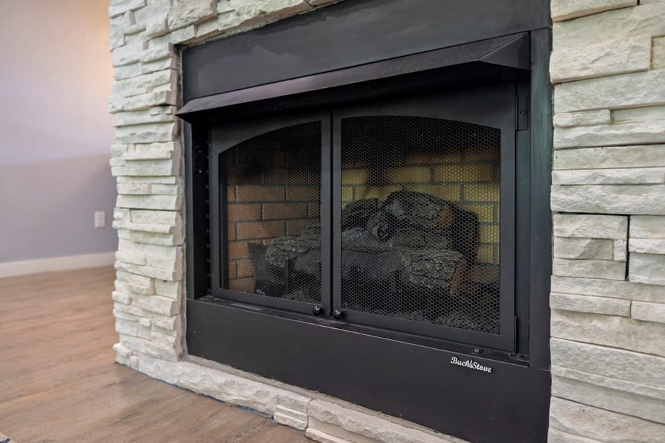 A close view highlights the modern black firebox and textured white stone surround in the living room.
