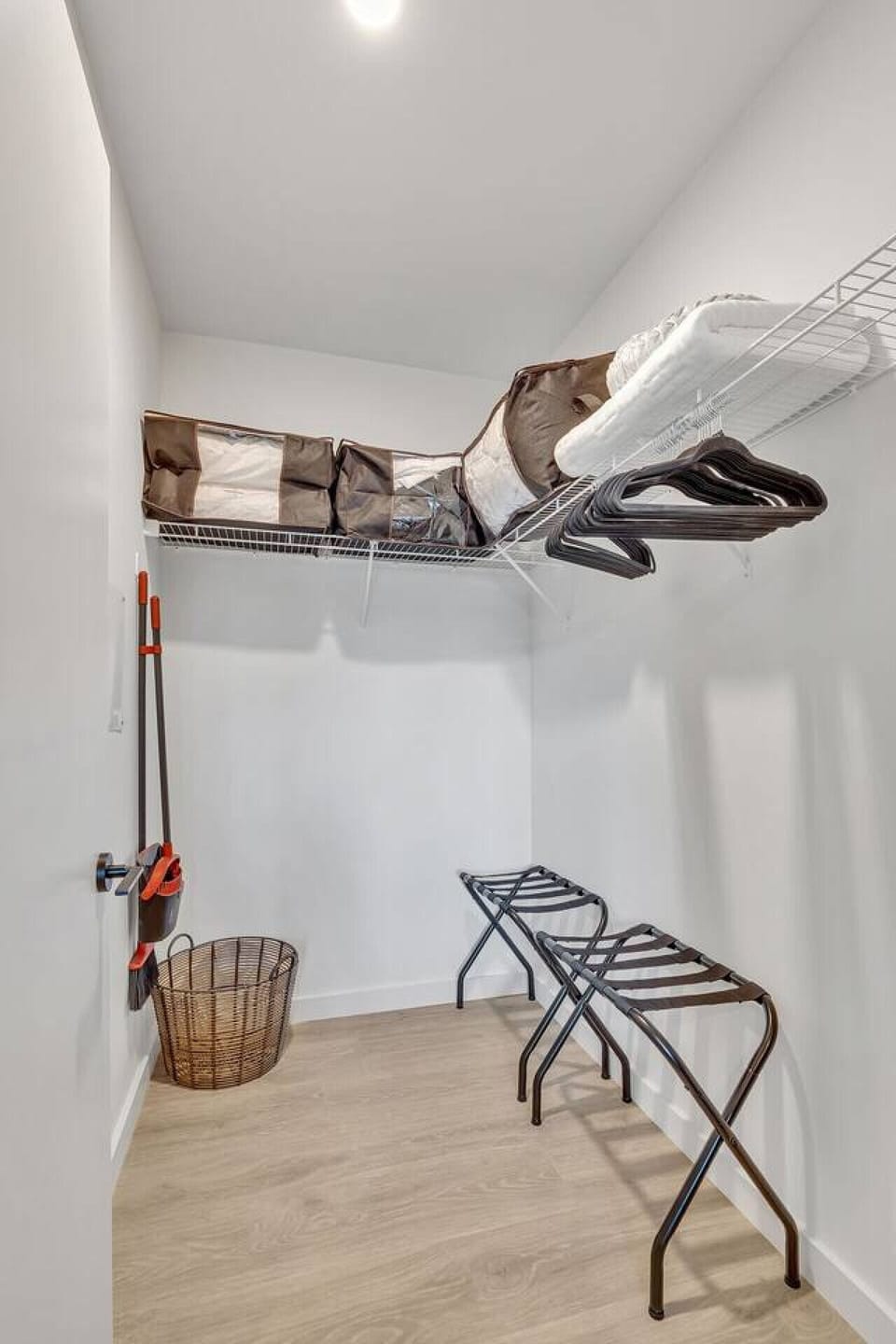 The Stage Walk-in closet with extra bedding, luggage racks, and laundry hamper.