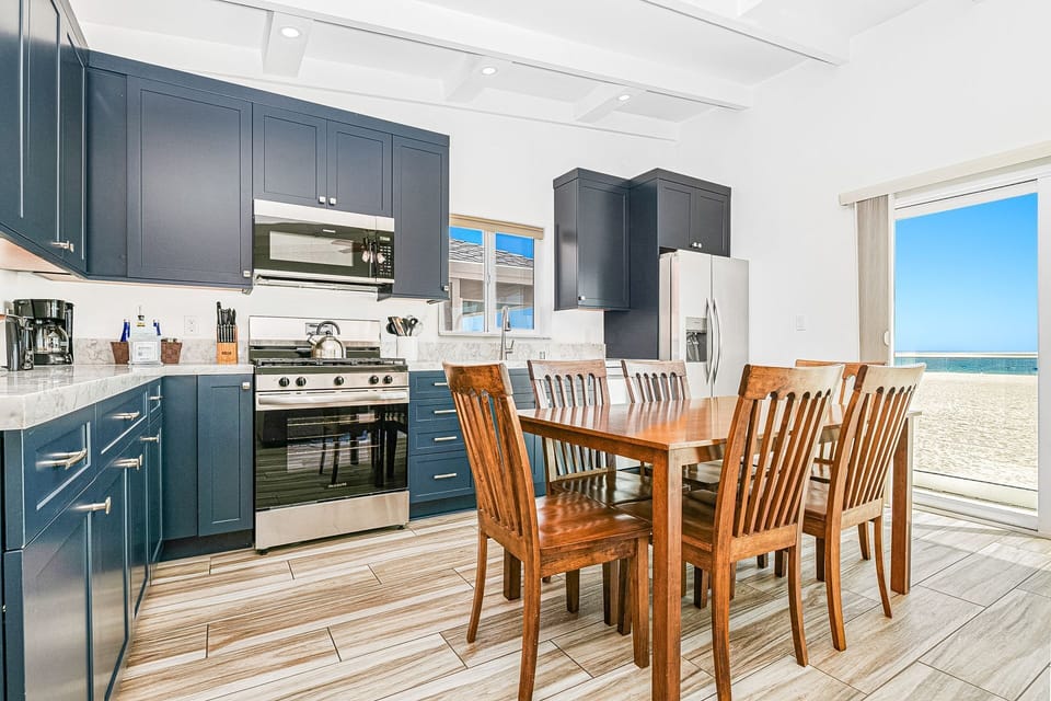The kitchen stretched along the wall beyond the dining area and is stocked with dishes, utensils, cookware, bakeware, and large and small appliances.
                