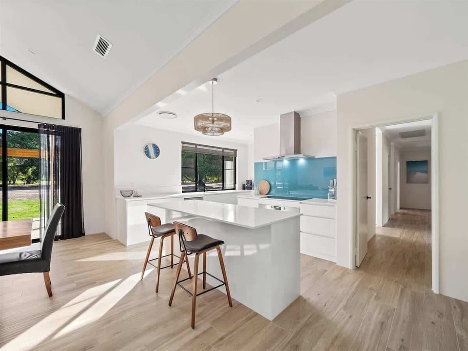The stylish kitchen is fully equipped with modern appliances, stone benchtops, and a breakfast bar for easy meals.